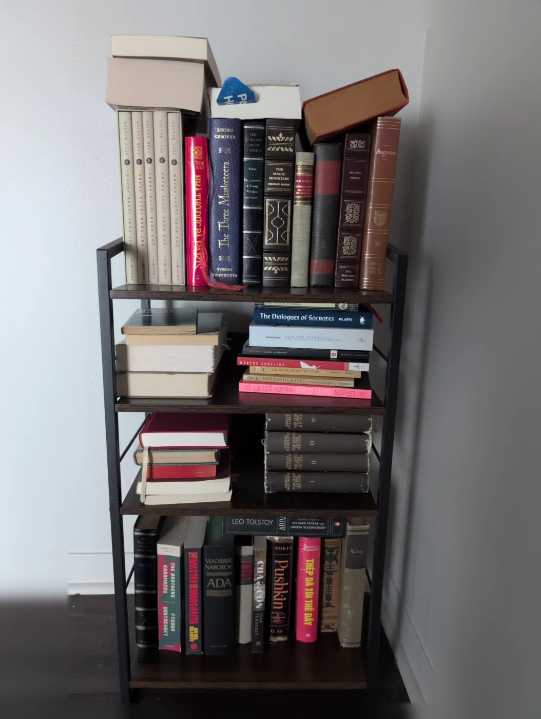 A four shelf bookcase filled with hardback and paperback classics.